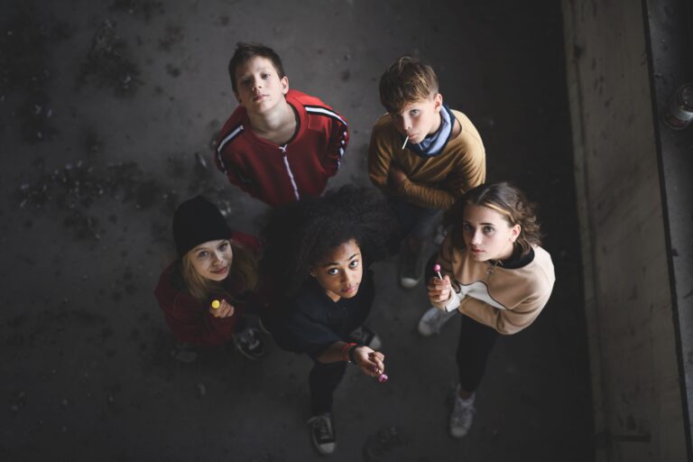 Top view of group of teenagers gang standing indoors in abandoned building, looking at camera.