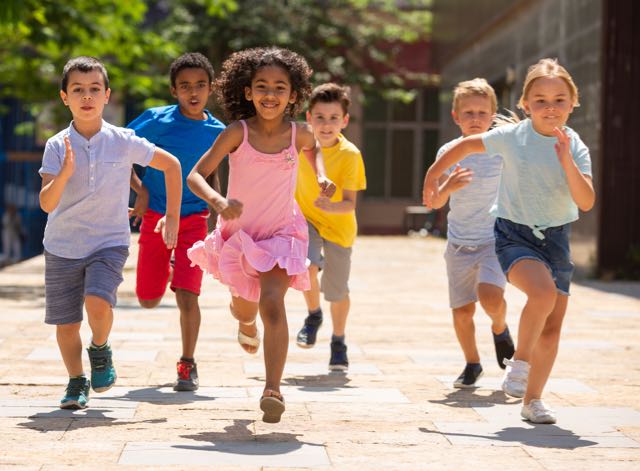 Team of positive kids running in race in the street and laughing