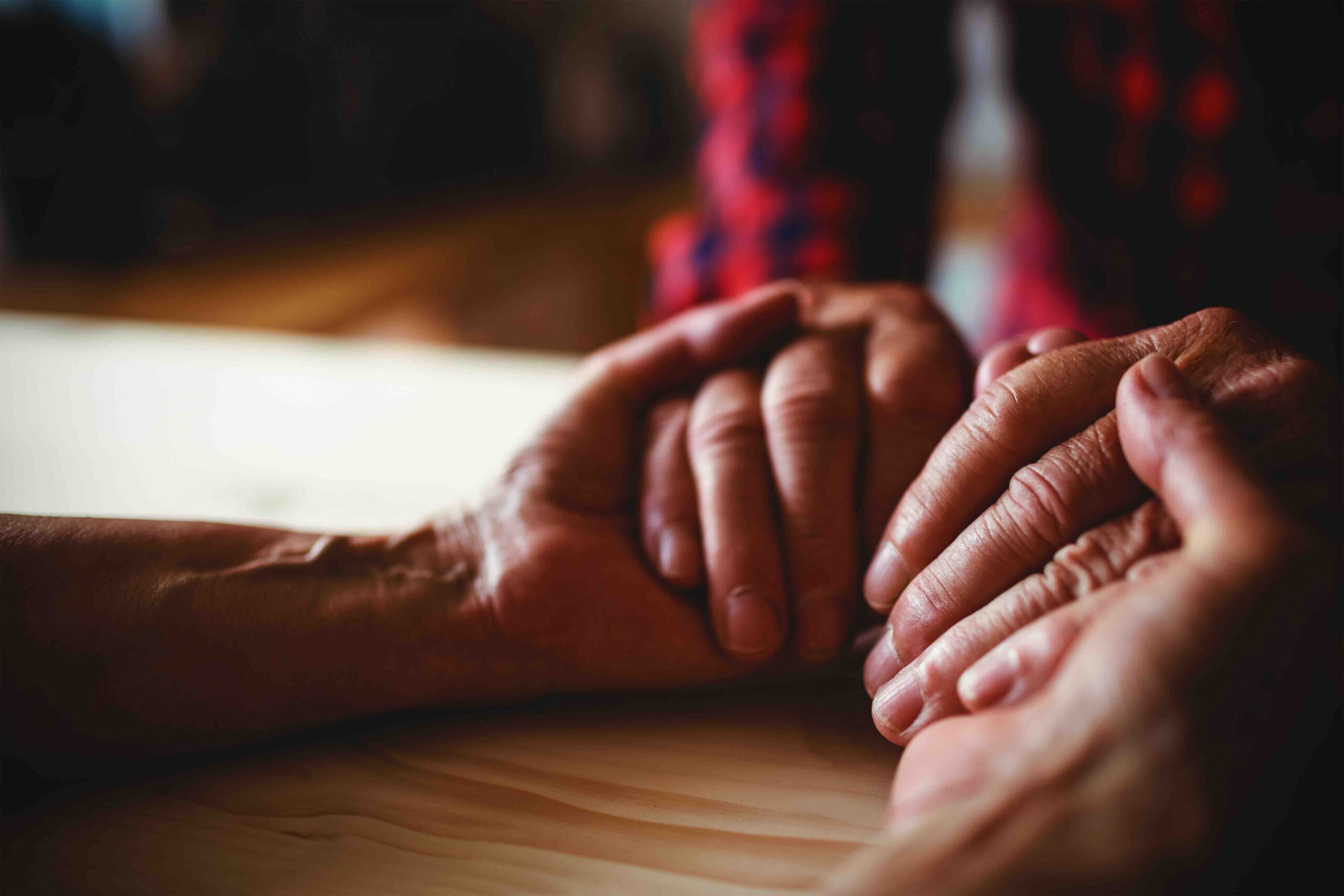Close-up of senior couple holding hands at home