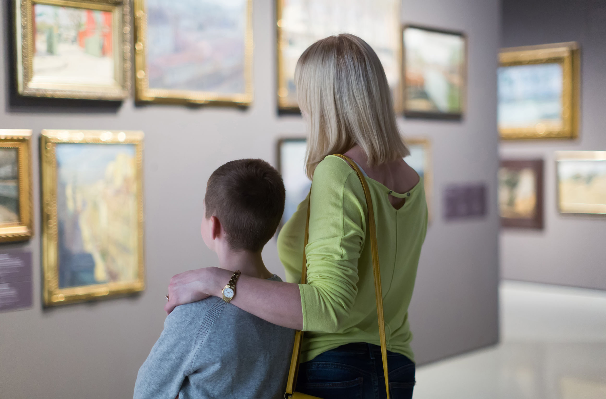 Mother and son looking at paintings in halls of museum