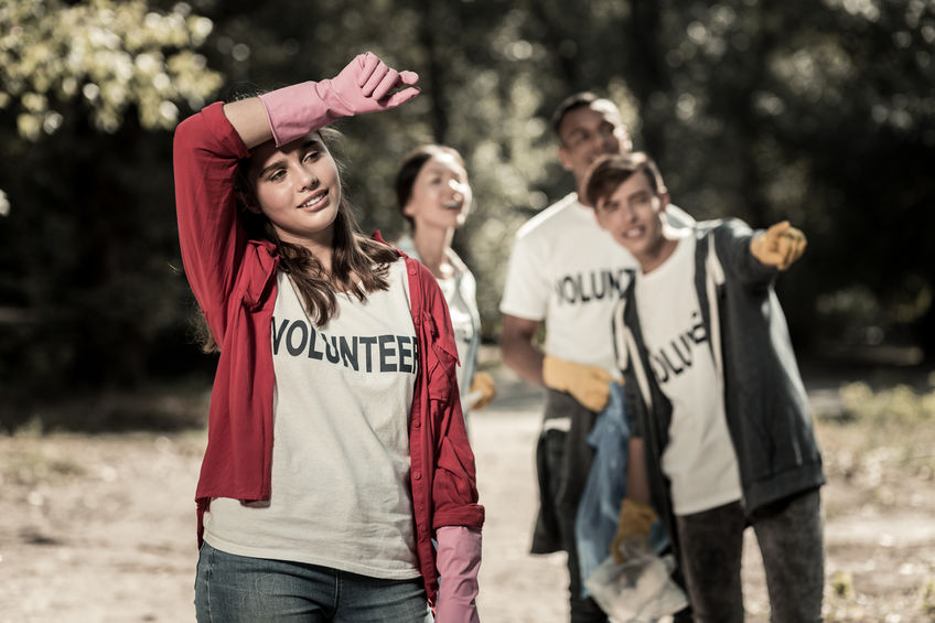 Dark-haired girl wearing pink gloves feeling tired after volunteering all day