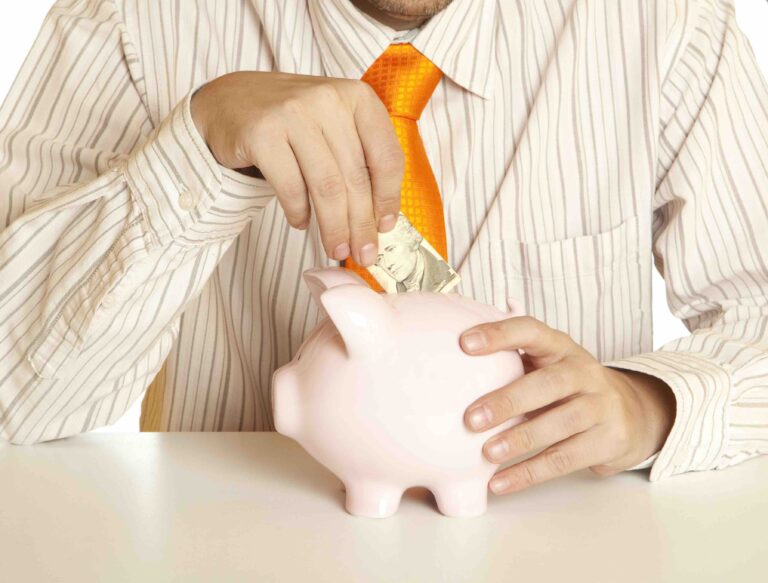 15422266 - male hand putting coins into a piggy bank
